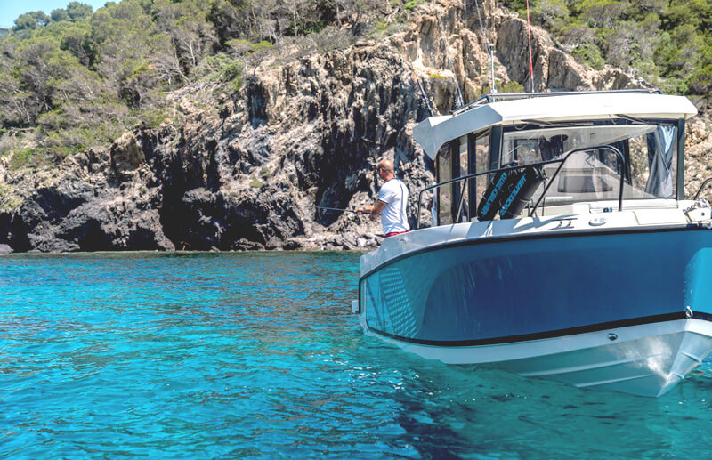 Quicksilver 705 Pilothouse, man vist vanaf boot bij rotsen