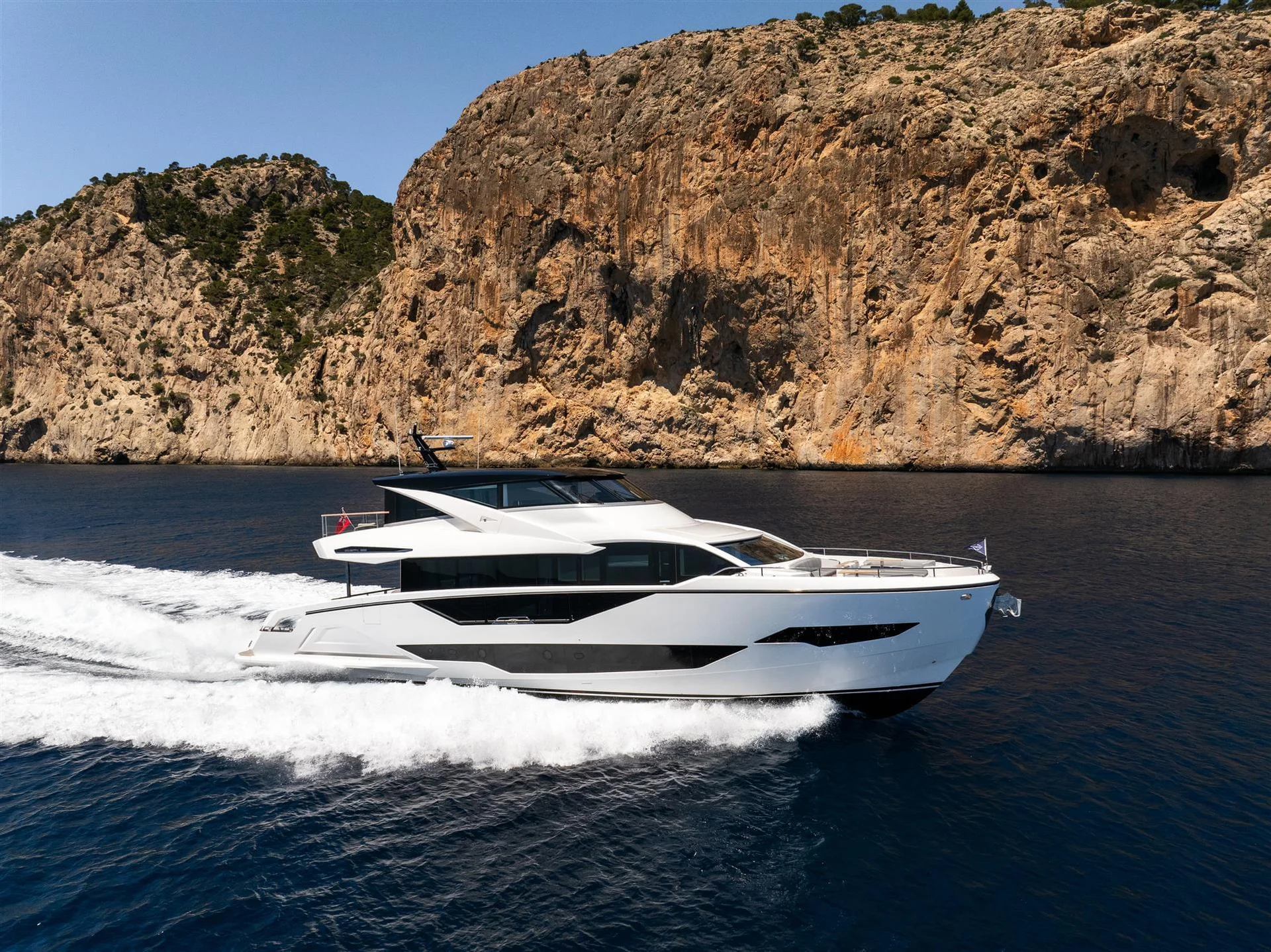 Sunseeker 90 Ocean Enclosed, jacht varend langs rotsachtige kust