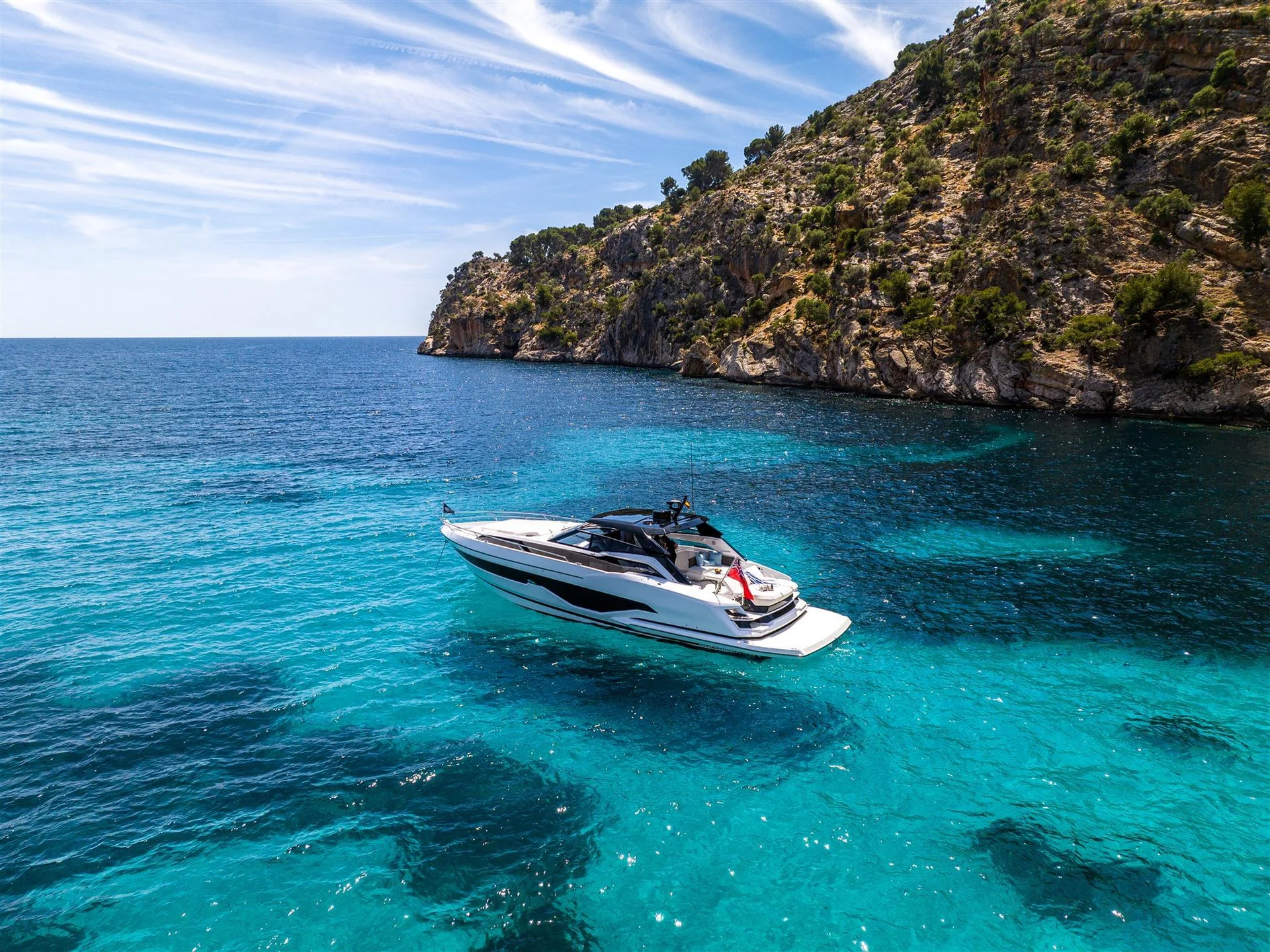 Sunseeker Superhawk 55, jacht op turquoise water bij kust