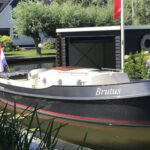 Vedette Brutus BR 8.50, zwarte motorboot afgemeerd bij botenhuis