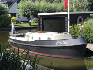 Vedette Brutus BR 8.50, zwarte motorboot afgemeerd bij botenhuis