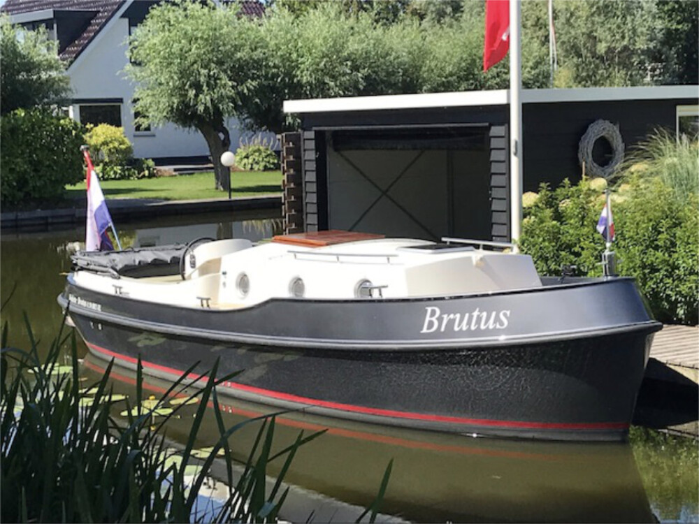 Vedette Brutus BR 8.50, zwarte motorboot afgemeerd bij botenhuis