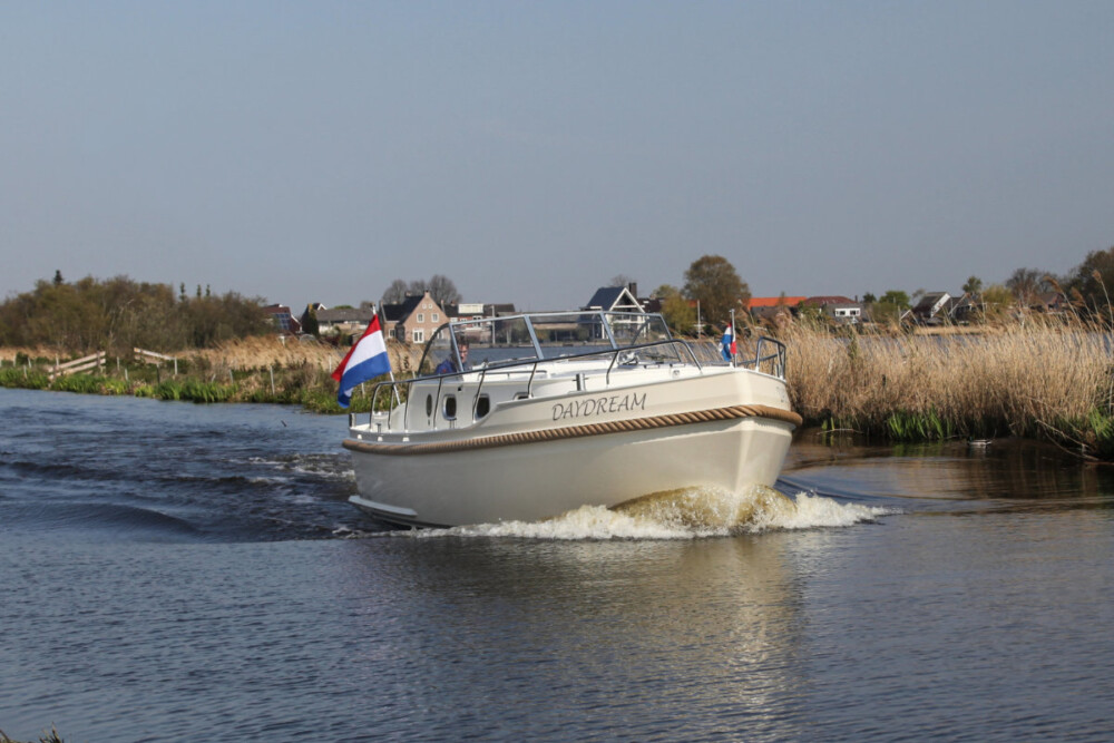 Vedette Cabin Classic Line 29 ft, boot varend op rivier met nederlandse vlag
