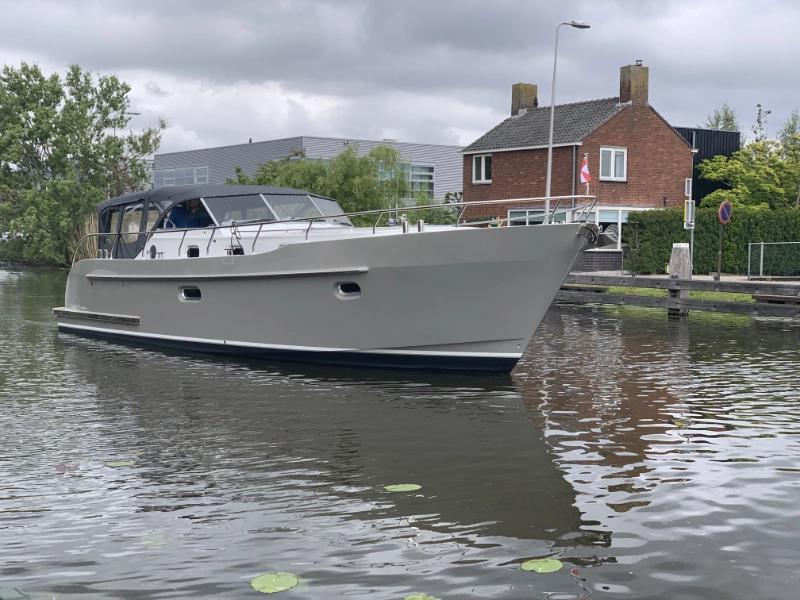 Vedette Cabin Comfort Line 37 ft, grijze motorboot aangemeerd bij huis