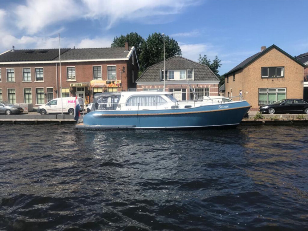 Vedette Salon Classic Line 36 ft, blauwe motorboot afgemeerd bij huizen