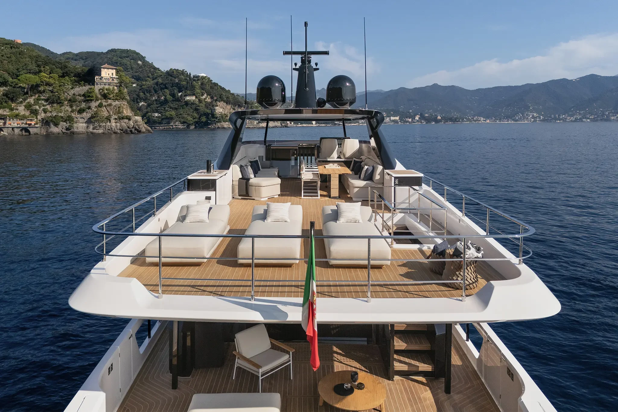 Ferretti Infynito 80, voordek met loungebanken en zicht op kust