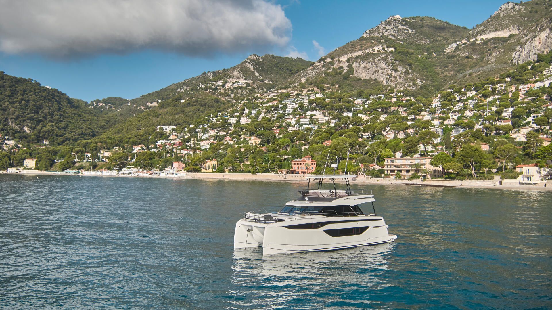 Prestige M48, catamaran voor de anker bij kustdorp