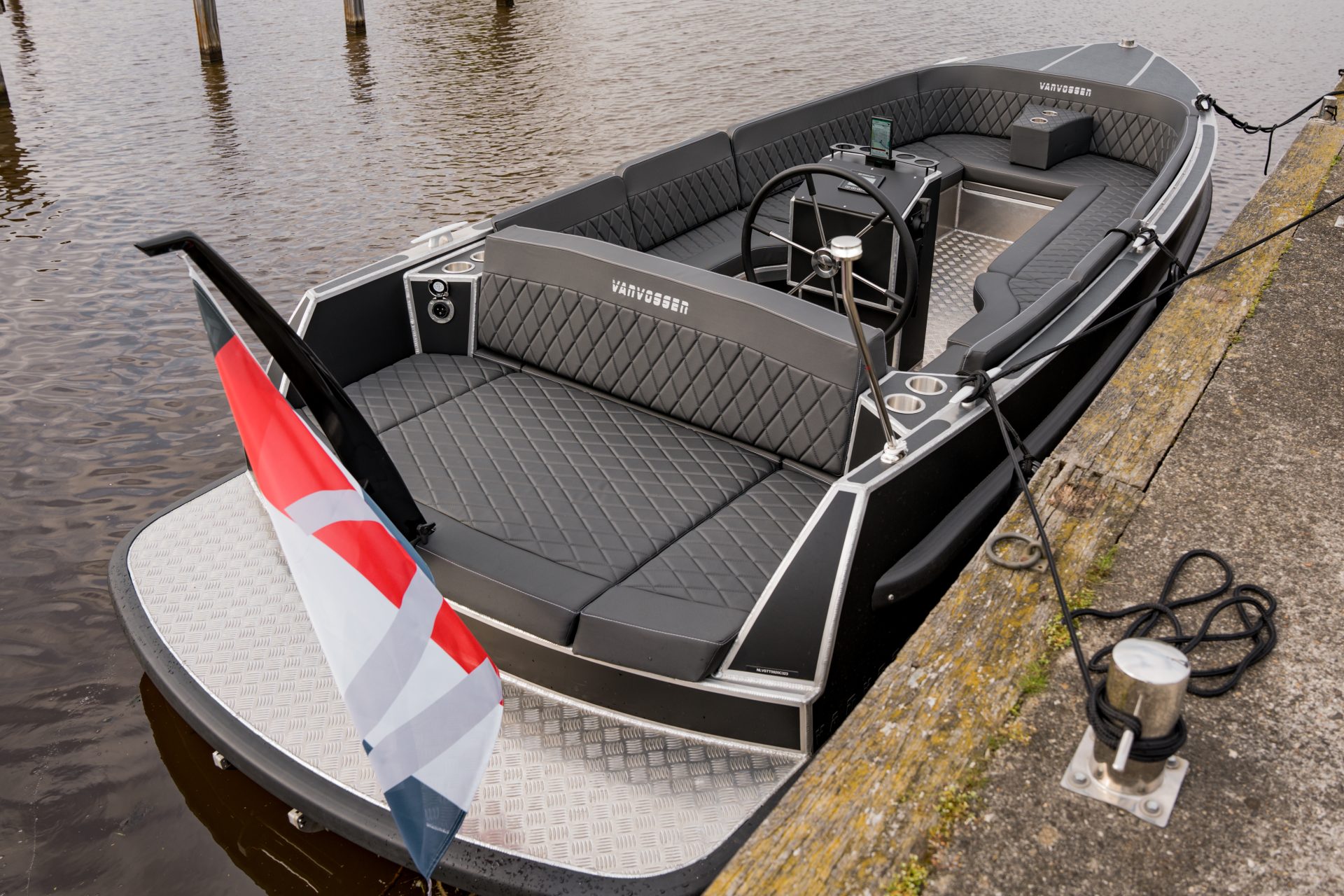 Van Vossen Plugin-E-Tender 595, boot bij aanlegsteiger met vlag