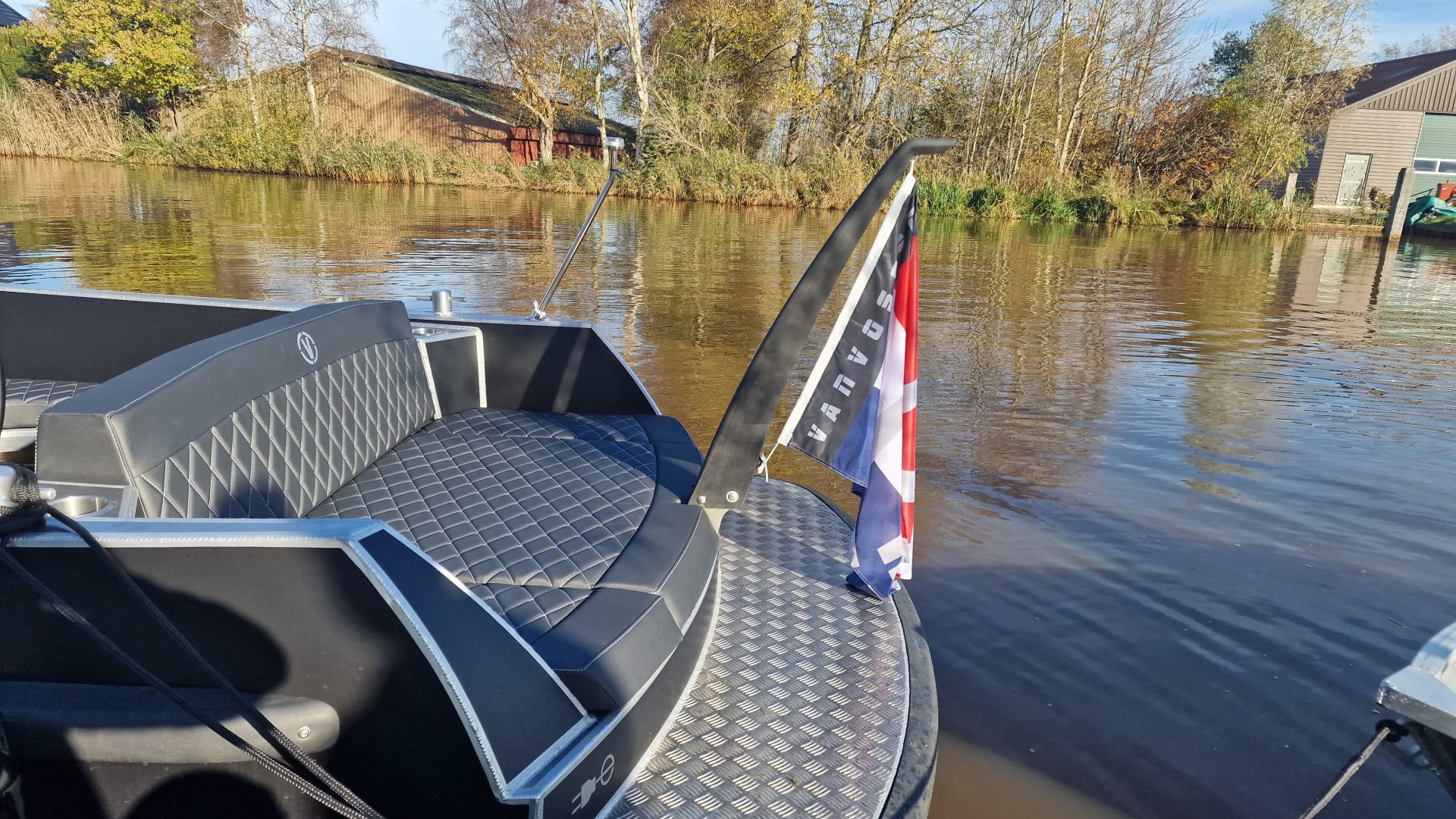 Van Vossen Plugin-E-Tender 595, boot met zitbank en vlag op water