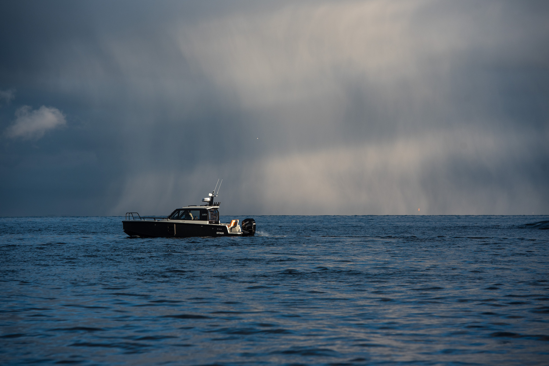 XO DFNDR 8, boot varend op zee onder onweerslucht